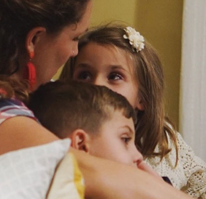 A woman reads a story to a boy and girl