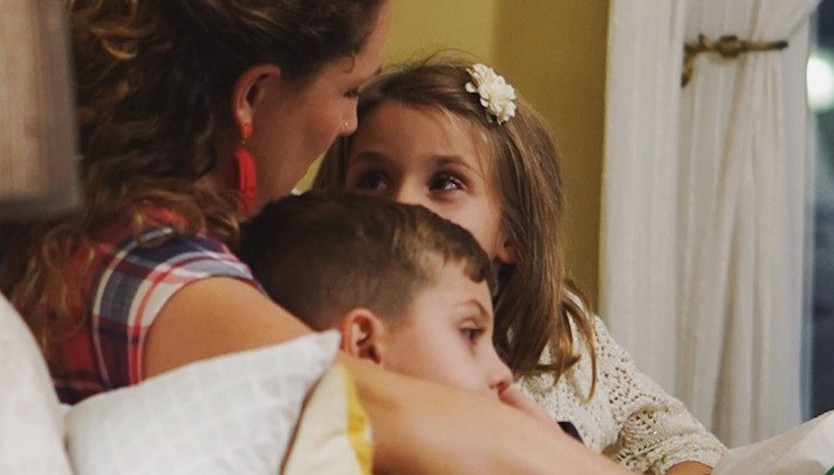 A woman reads a story to a boy and girl