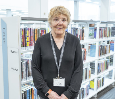Photo of Library volunteer in front of a bookshelf