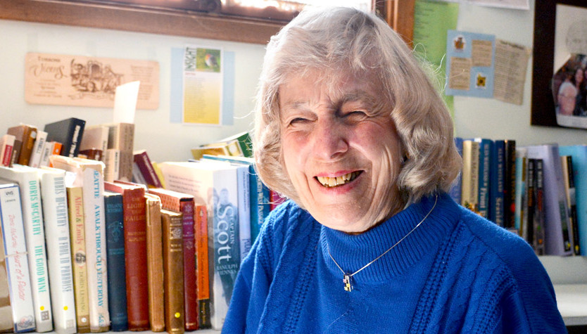 Norma High in the Calgary Public Library in front of books on shelves.