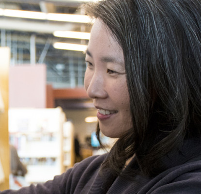 Teresa Wong selecting a book from a shelf in a library.