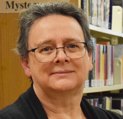 Photograph of Giselle Wong standing in front of a bookshelf. 