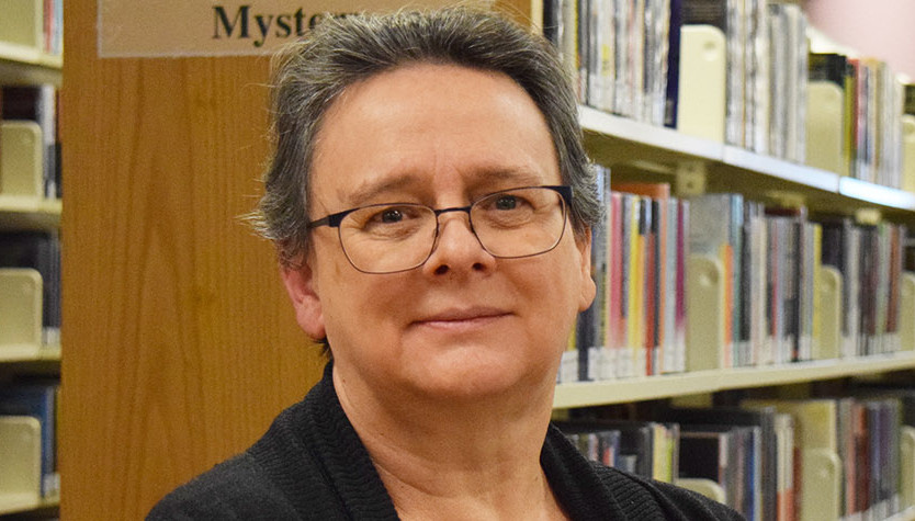 Photograph of Giselle Wong standing in front of a bookshelf. 