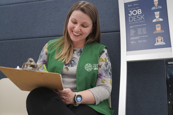 A Calgary Public Library volunteer writing on a clipboard.