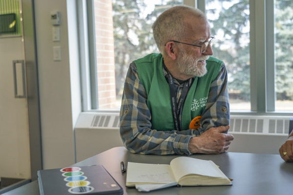 A Calgary Public Library volunteer sitting at a table with an open book.