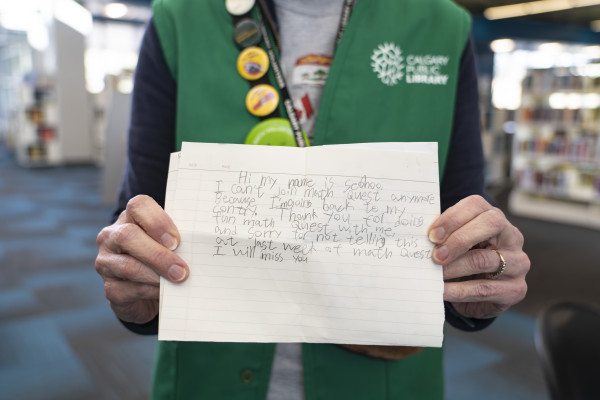 A Calgary Public Library volunteer holds a note written by a young patron.