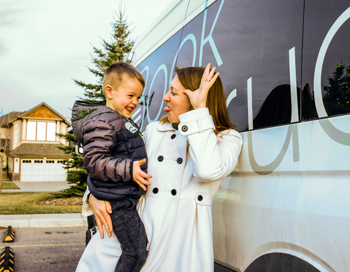 background image: A woman playfully makes a funny face while holding a laughing young boy beside a vehicle labeled "Book Truck".