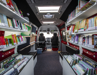 An inside view of a vehicle with bookshelves filled with books.