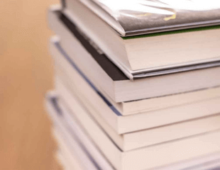 A photograph of a stack of books on a table. 