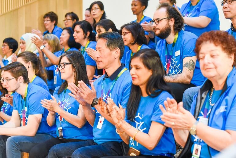 background image: Photo of a group of people wearing blue shirts