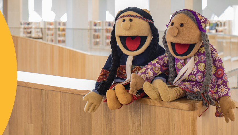 An image of two puppets designed as indigenous people with an overlay of a graphic of a table with math work sheets and a cup with pencils.