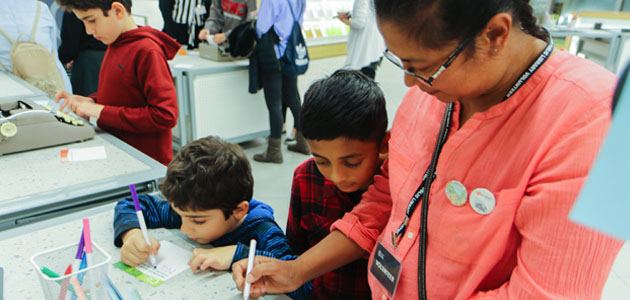 Children colouring at a table with an adult in a library.