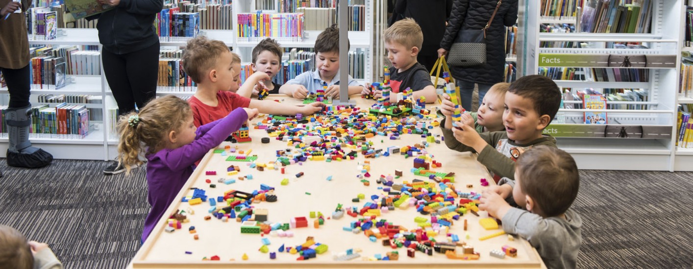 A group of children sitting around a table and building with lego.