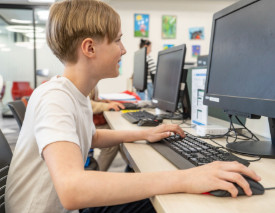 A child uses a desktop computer at a Library workstation.