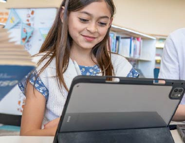 Child using a tablet device in a library learning space.