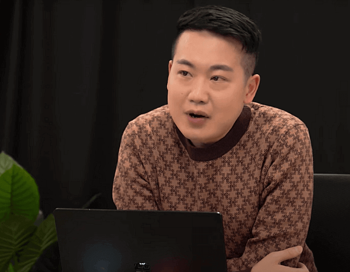 background image: A photo of an adult in midst of a conversation. He is leaning against a table and their is a laptop in front of him. 