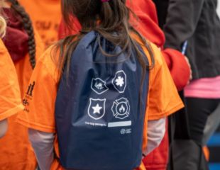 Child wearing a Leaders and Readers backpack at a library event.
