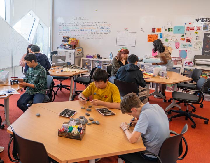 background image: Teens working on creative projects in a library makerspace.