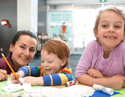 A woman and two children doing a drawing activity.