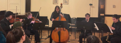 A young professional musicians collective playing instruments such as the cello, violins and the flute for an audience.
