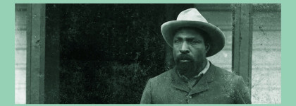 Green banner with a historic black-and-white portrait of a bearded man wearing a wide-brimmed hat and suit used to promote Historian in Residence program about John Ware