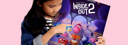 Person points to a colorful Inside Out 2 poster showing several animated emotion characters, including Joy, Anger, and other new characters, on a pink background.