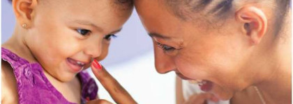 Adult and young child touching foreheads and interacting playfully at close range.