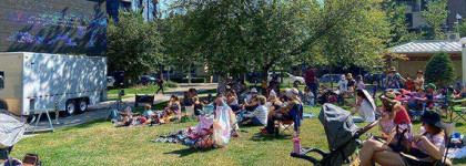 People sitting on the grass watching a large movie screen.