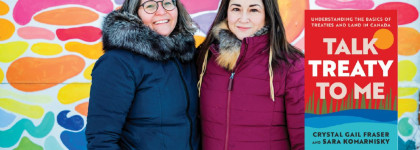 Two people standing in front of a colourful mural, with the book cover Talk Treaty to Me: Understanding the Basics of Treaties and Land in Canada displayed beside them.