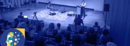 Two people on stage with an audience shaded blue to promote the AI and the Arts A Community Conversation social 1300x600 2