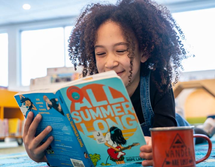 Child reading a popular Juvenile Fiction book called All Summer Long, used to promote the Ultimate Summer Challenge, or USC 2026.