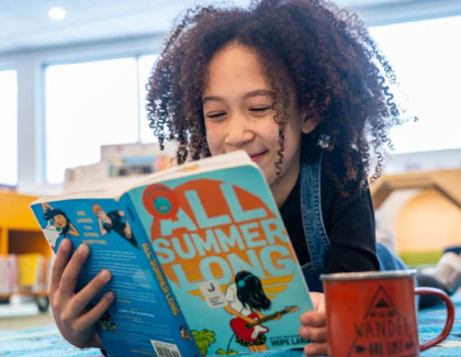Child reading a popular Juvenile Fiction book called All Summer Long, used to promote the Ultimate Summer Challenge, or USC 2026.
