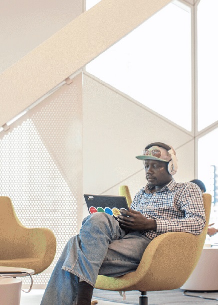 A man sitting in a chair wearing headphones and using a laptop.