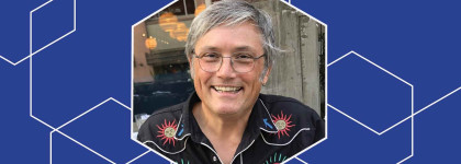 Headshot of 2026 Creative in Residence AIC Paul Freeman surrounded by a blue border with white geometric pattern.