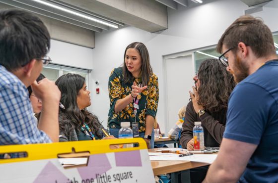 A woman explaining a concept to a group of people at a workshop.