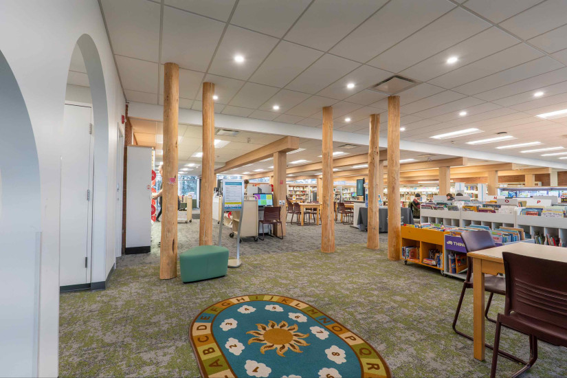 early learning centre at Louise Riley Library with wood pillars, a round mat and bookshelves.